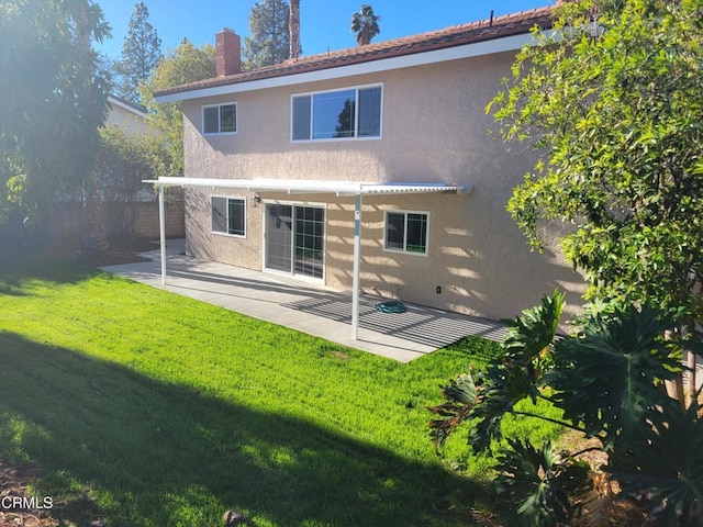 back of property with a lawn and a patio area