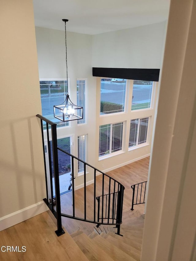 stairway with wood-type flooring and an inviting chandelier