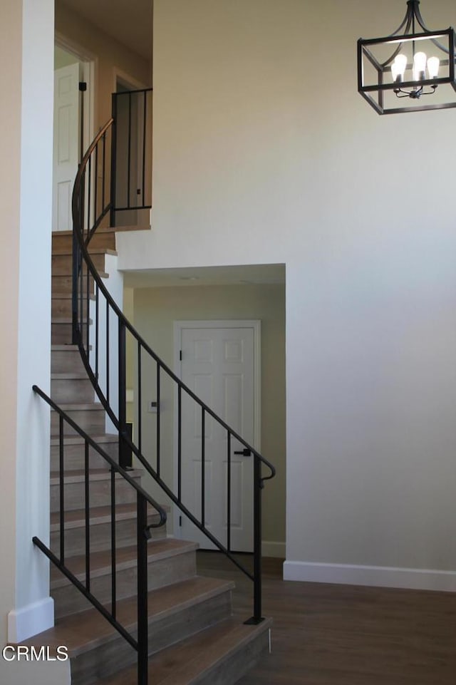 stairway with hardwood / wood-style flooring and a notable chandelier