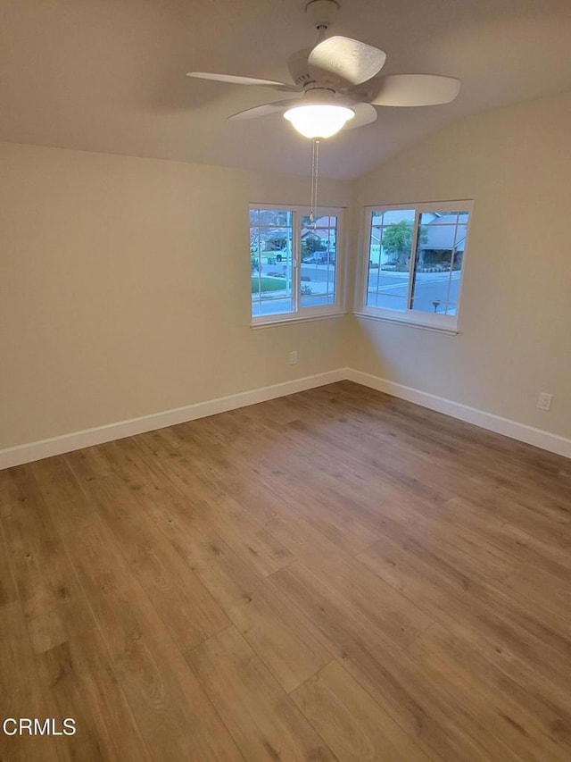 empty room with ceiling fan, light wood-type flooring, and lofted ceiling