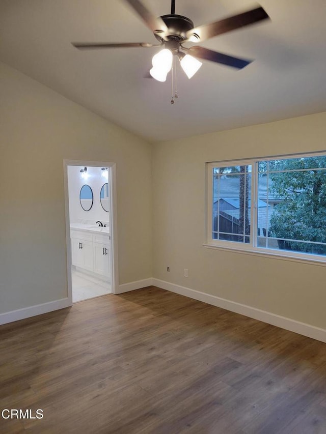 empty room with hardwood / wood-style flooring, ceiling fan, lofted ceiling, and sink