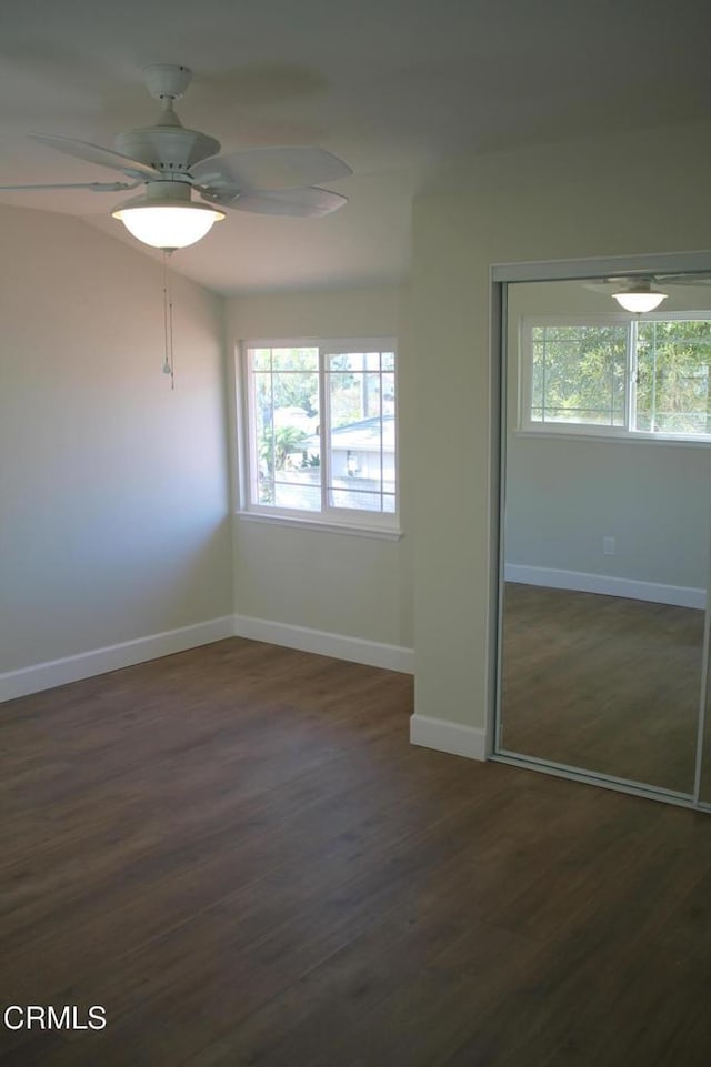 unfurnished bedroom with a closet, dark hardwood / wood-style floors, multiple windows, and ceiling fan