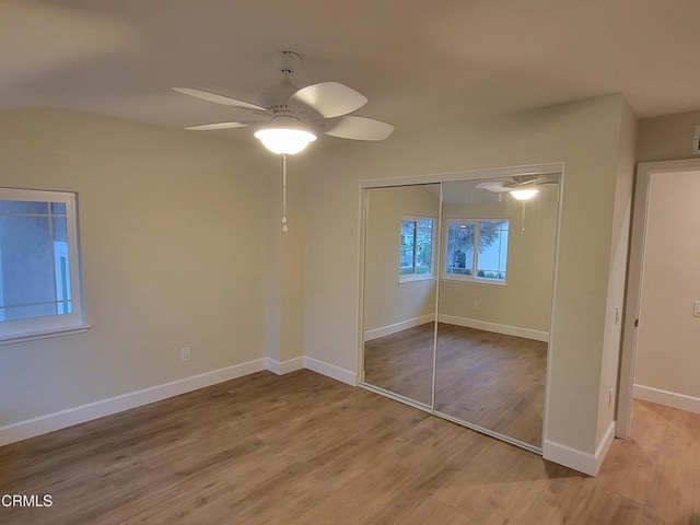 unfurnished bedroom featuring ceiling fan, light hardwood / wood-style floors, and a closet