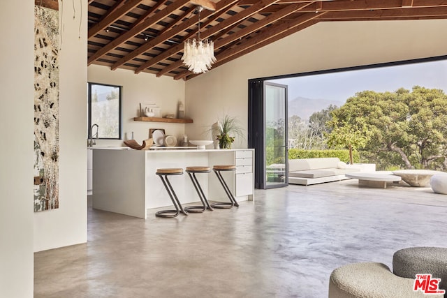 bar with concrete flooring, a mountain view, lofted ceiling with beams, and a notable chandelier