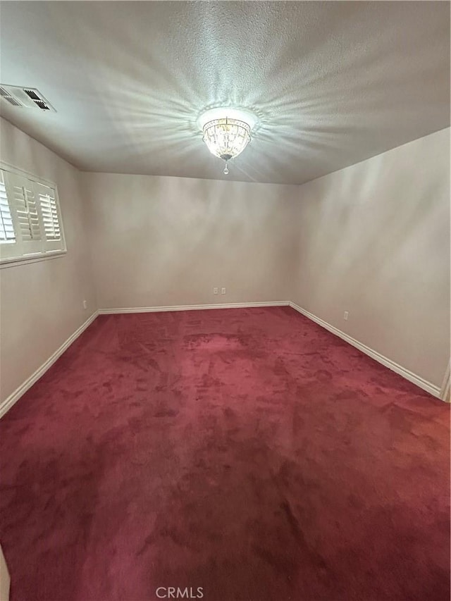 carpeted empty room featuring a textured ceiling