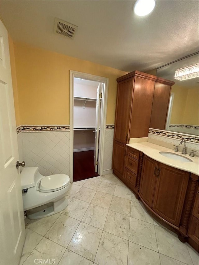 bathroom featuring vanity, toilet, and tile walls