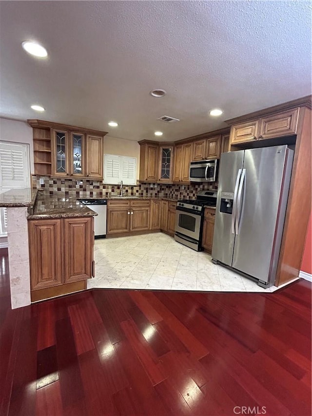 kitchen featuring light wood-type flooring, stainless steel appliances, and dark stone counters