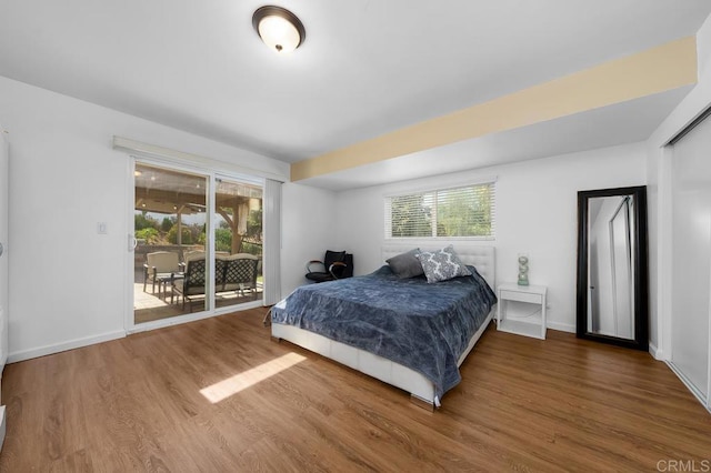 bedroom with multiple windows, hardwood / wood-style flooring, and access to exterior