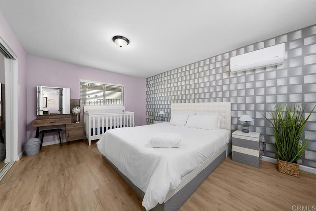 bedroom featuring light hardwood / wood-style floors and a wall mounted AC