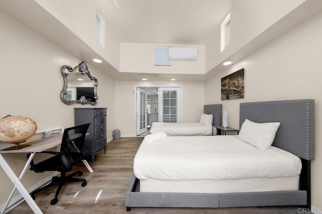 bedroom featuring a high ceiling, an AC wall unit, and wood-type flooring