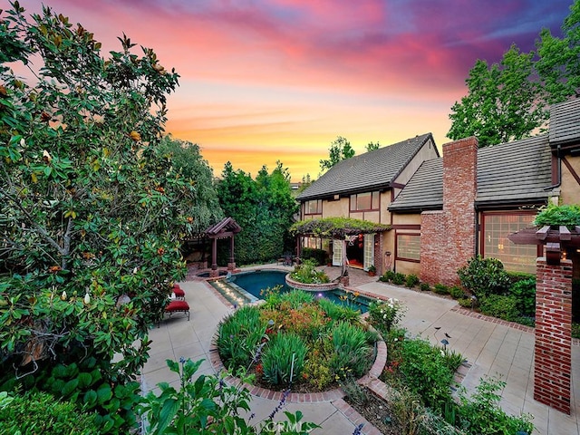 pool at dusk featuring a patio area