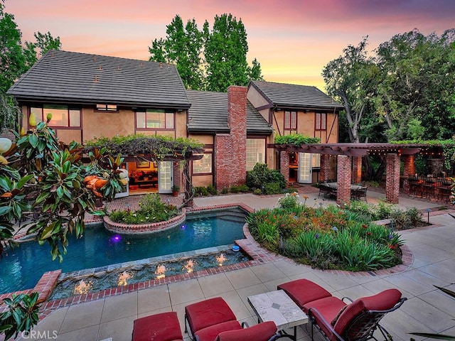 pool at dusk with a pergola and a patio area