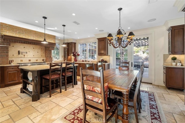 dining area featuring ornamental molding, sink, and a notable chandelier