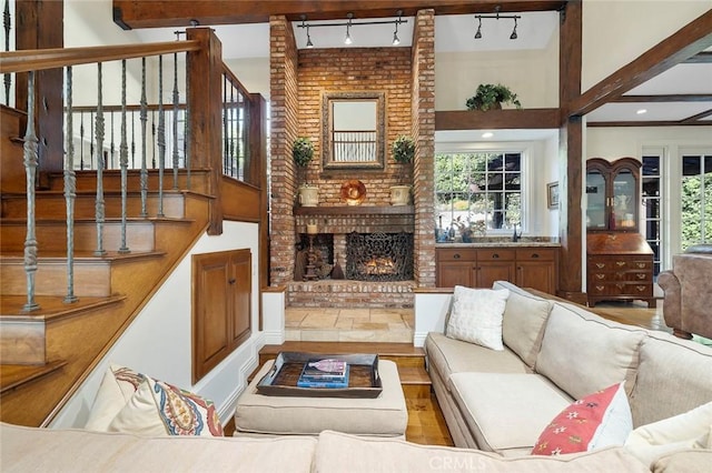 living room featuring plenty of natural light, a fireplace, beam ceiling, and rail lighting