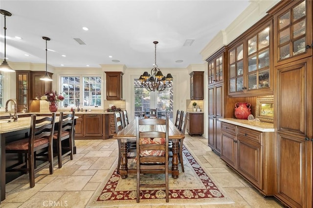 dining space featuring ornamental molding, sink, and a notable chandelier