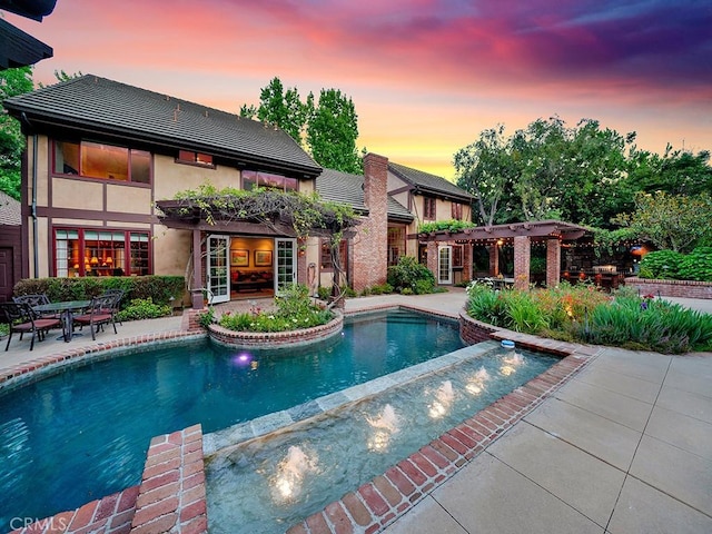 pool at dusk with a pergola and a patio