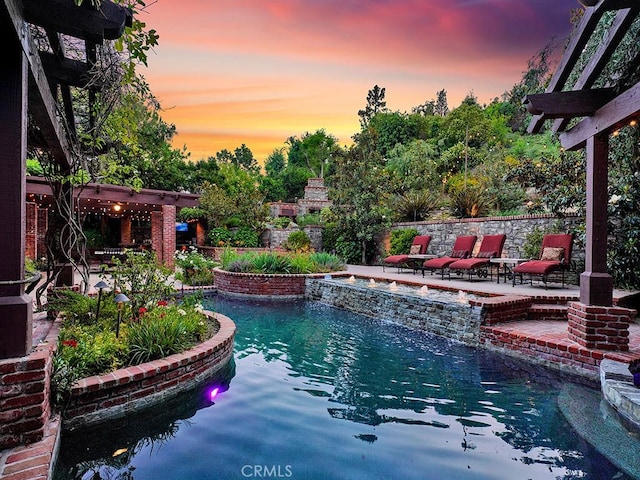 pool at dusk featuring a pergola and a patio