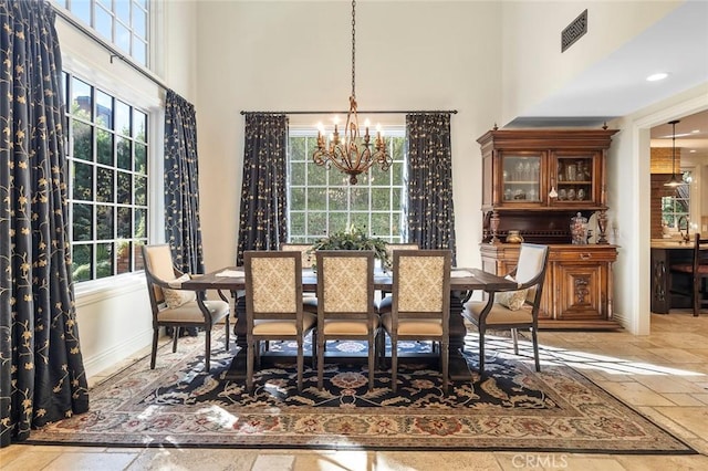 dining room featuring an inviting chandelier and a towering ceiling