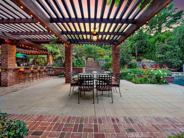 patio terrace at dusk with a pergola and an outdoor bar