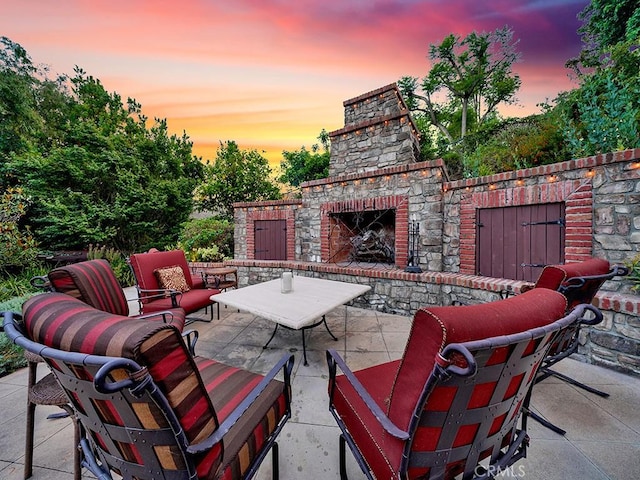 patio terrace at dusk featuring exterior fireplace