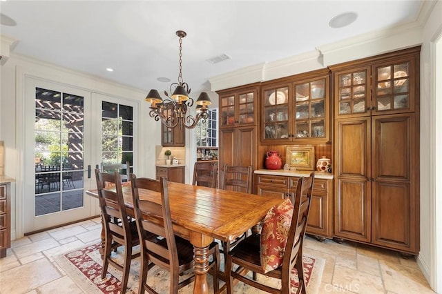 dining area featuring ornamental molding, an inviting chandelier, and french doors