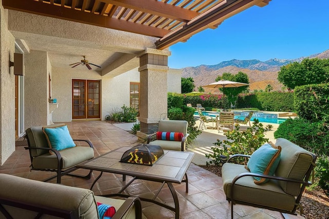 view of patio with an outdoor fire pit, ceiling fan, a pergola, a fenced in pool, and a mountain view