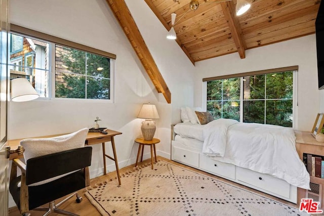 bedroom featuring vaulted ceiling with beams, light hardwood / wood-style flooring, and multiple windows