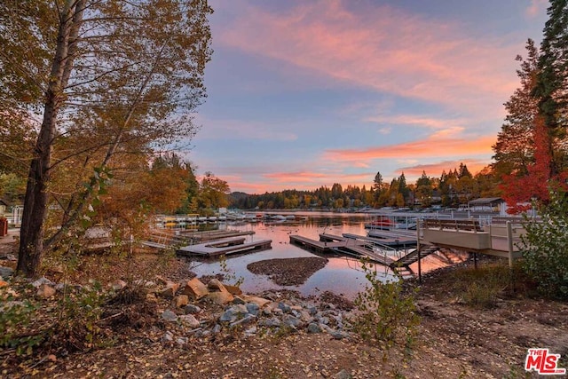 yard at dusk featuring a dock and a water view