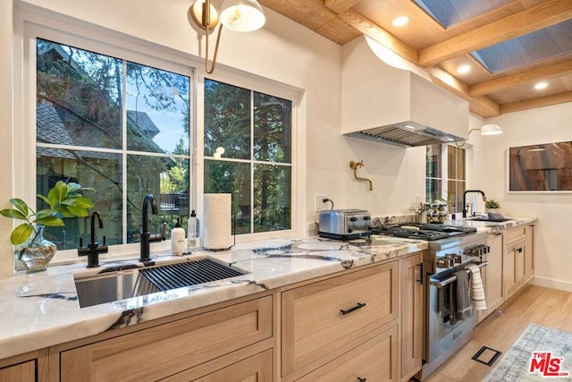 kitchen featuring stainless steel range, sink, beamed ceiling, and light hardwood / wood-style floors