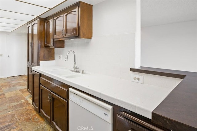 kitchen with sink, backsplash, tile countertops, white dishwasher, and dark brown cabinets