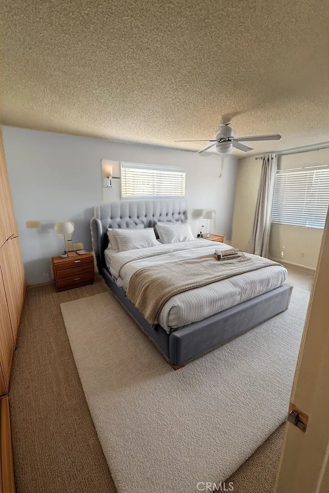 carpeted bedroom with ceiling fan and a textured ceiling