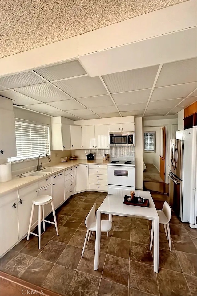 kitchen with white cabinetry, sink, a drop ceiling, and appliances with stainless steel finishes