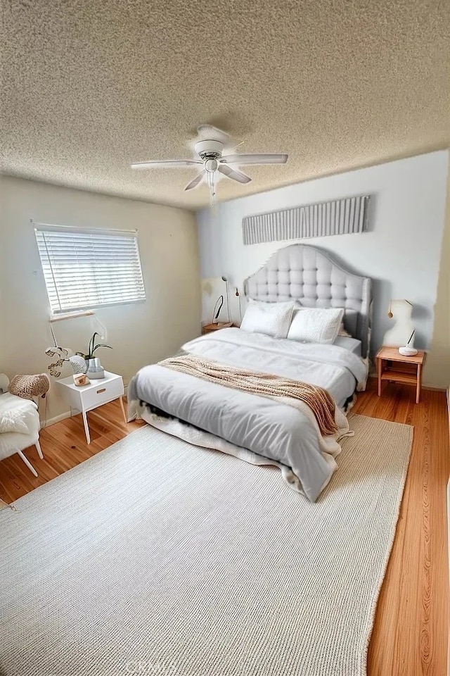 bedroom with hardwood / wood-style flooring, ceiling fan, and a textured ceiling