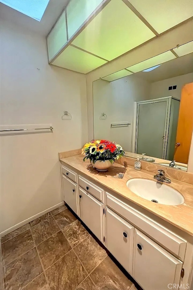 bathroom featuring vanity, walk in shower, and a skylight