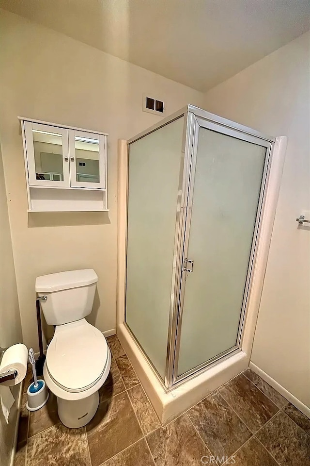 bathroom with toilet and a shower with shower door