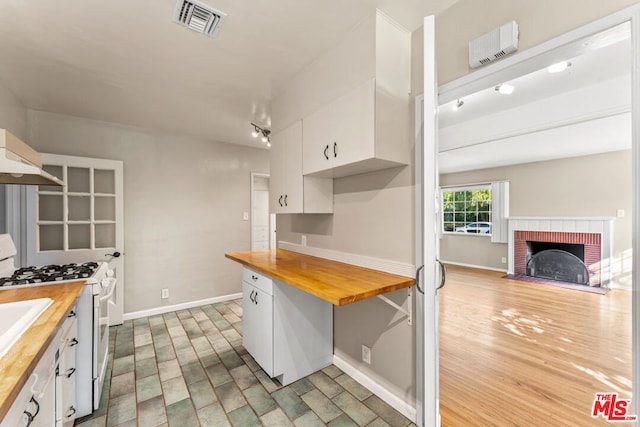 kitchen featuring wooden counters, white range with gas stovetop, and white cabinets