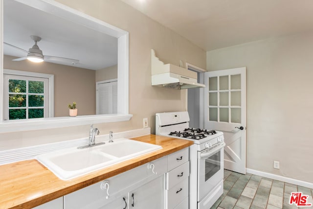 kitchen featuring white cabinetry, gas range gas stove, sink, ceiling fan, and wooden counters