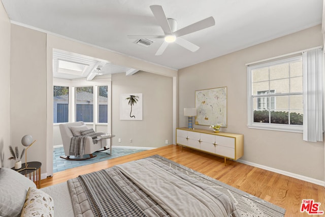 interior space featuring wood-type flooring, a skylight, ceiling fan, and beam ceiling