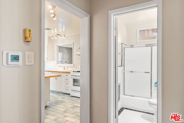 full bathroom featuring toilet, combined bath / shower with glass door, and sink