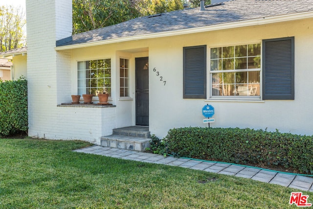 view of exterior entry with a lawn