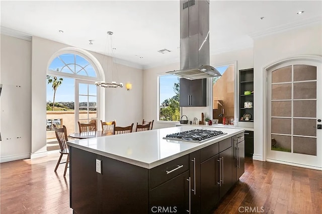 kitchen with a center island, crown molding, dark hardwood / wood-style floors, island exhaust hood, and stainless steel gas cooktop