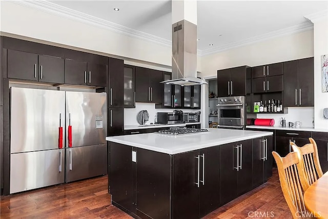 kitchen with island exhaust hood, dark hardwood / wood-style flooring, stainless steel appliances, crown molding, and a kitchen island