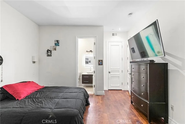 bedroom with connected bathroom and hardwood / wood-style flooring