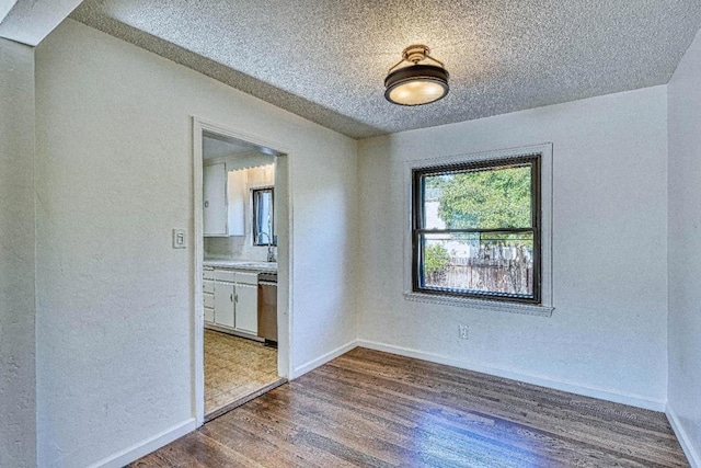 unfurnished room featuring dark wood-type flooring, sink, and a textured ceiling