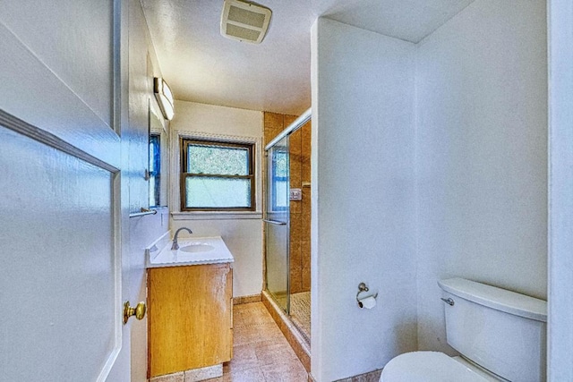 bathroom featuring tile patterned flooring, vanity, walk in shower, and toilet