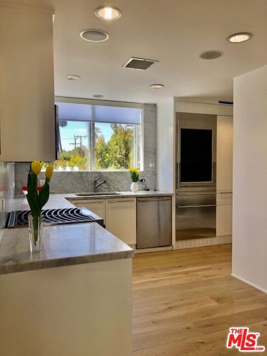 kitchen with dishwasher, white cabinets, sink, decorative backsplash, and light hardwood / wood-style floors