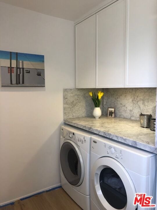 washroom with washing machine and clothes dryer, dark wood-type flooring, and cabinets