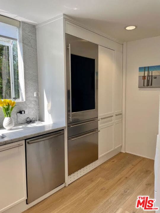 kitchen featuring white cabinets, dishwasher, and light hardwood / wood-style floors