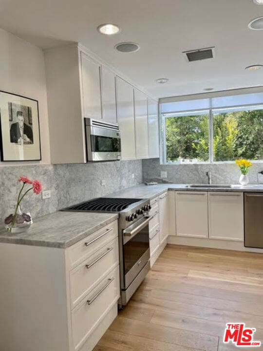 kitchen featuring light hardwood / wood-style flooring, white cabinets, and stainless steel appliances