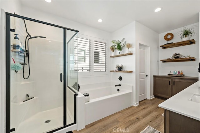 bathroom featuring vanity, wood-type flooring, and plus walk in shower